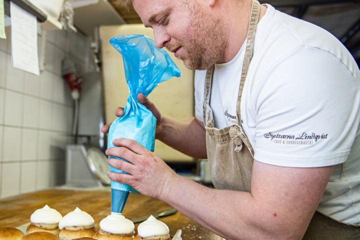 Martin Persson spritsar grädde på semlor.